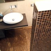 Bagno con pavimento materico e rivestimento mosaico